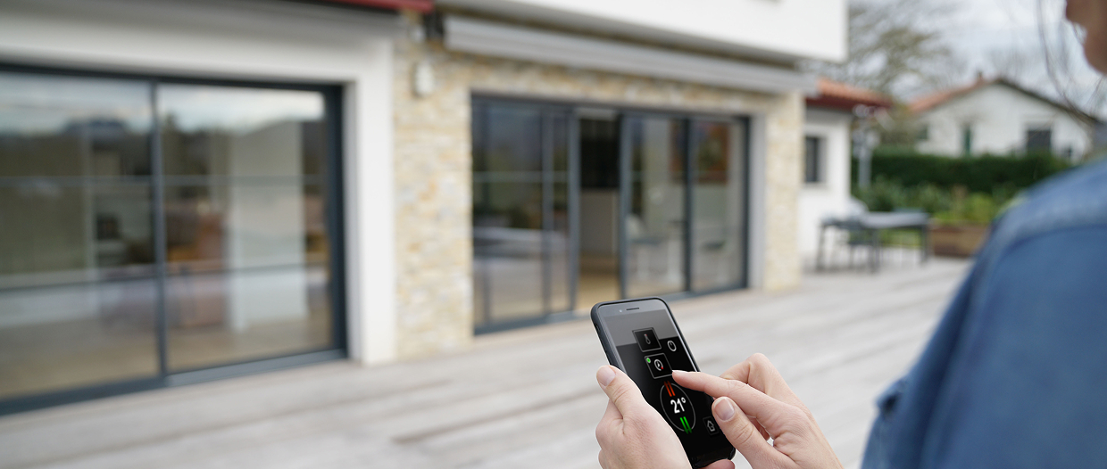 Contrôle de la domotique Degée via smartphone, réglant la température depuis l'extérieur d'une maison moderne
