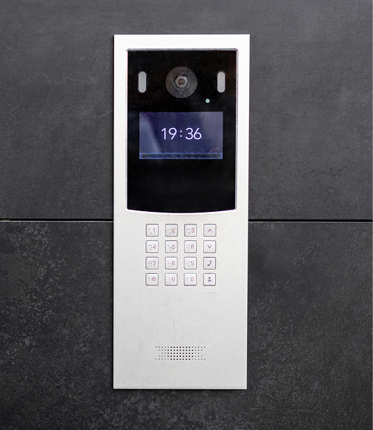 Interphone maison moderne Degee avec écran et clavier numérique, installé à côté d'une porte vitrée.